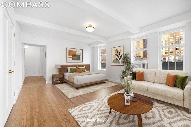 bedroom with light hardwood / wood-style flooring and beamed ceiling