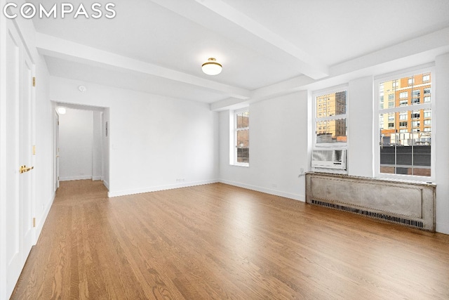 spare room featuring beam ceiling, wood-type flooring, and radiator heating unit