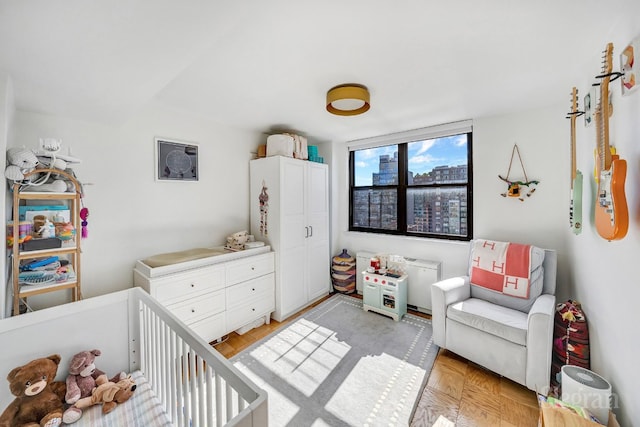 bedroom featuring light parquet flooring and a crib