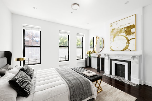 bedroom with a tile fireplace and dark hardwood / wood-style flooring