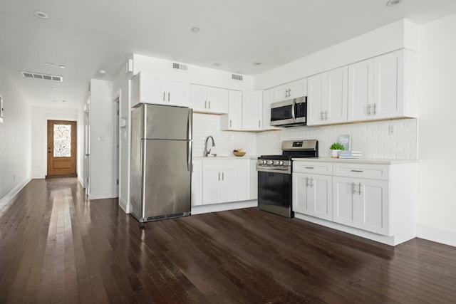 kitchen featuring white cabinetry, stainless steel appliances, dark wood-type flooring, and tasteful backsplash