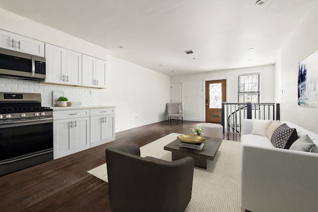 living area featuring visible vents, dark wood-style flooring, and baseboards