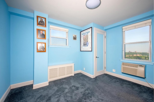 unfurnished room with a wall mounted AC and dark colored carpet