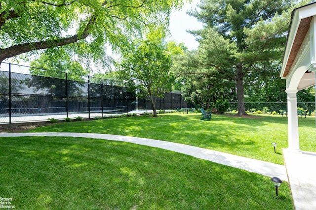 view of home's community featuring tennis court and a lawn