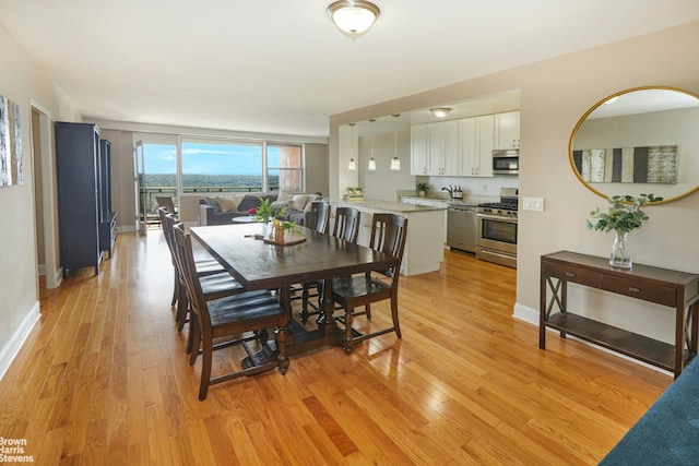 dining area featuring light wood-style flooring and baseboards