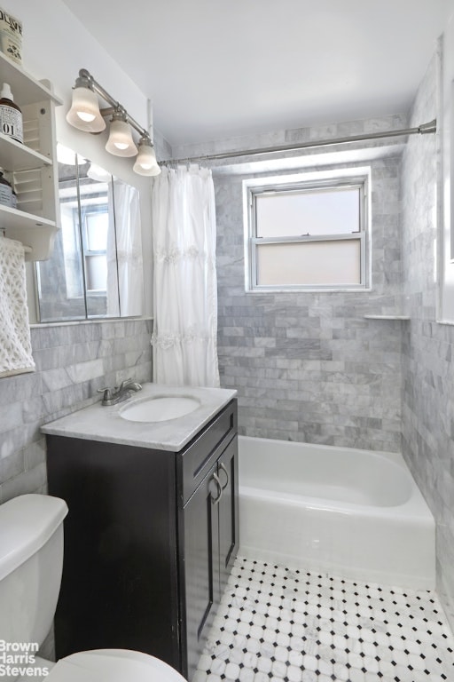 full bathroom with tile walls, tile patterned flooring, vanity, toilet, and shower / bath combo with shower curtain