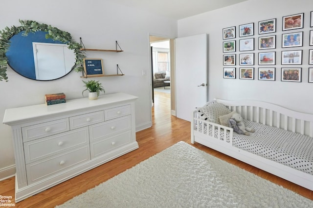 bedroom with light hardwood / wood-style flooring and a crib