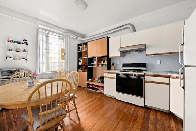 kitchen featuring hardwood / wood-style flooring, gas range, white cabinets, and backsplash