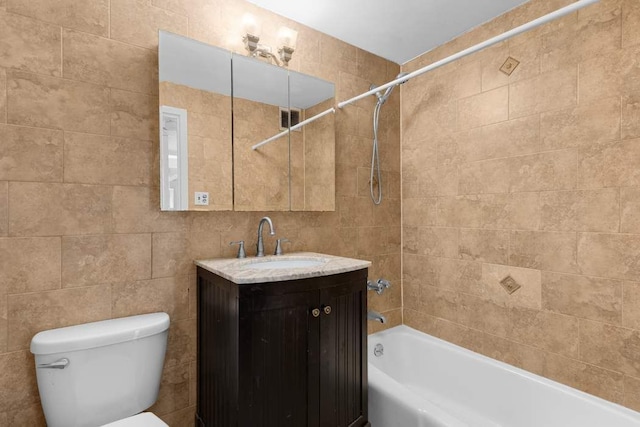 full bathroom with vanity, toilet, tiled shower / bath combo, and tile walls