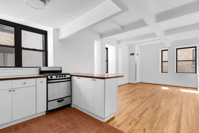 kitchen with white cabinetry, gas stove, beamed ceiling, and kitchen peninsula