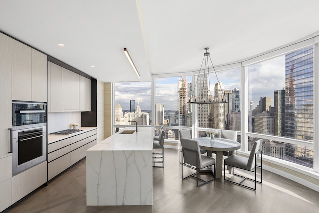 kitchen featuring decorative light fixtures, a sink, a view of city, modern cabinets, and a center island with sink