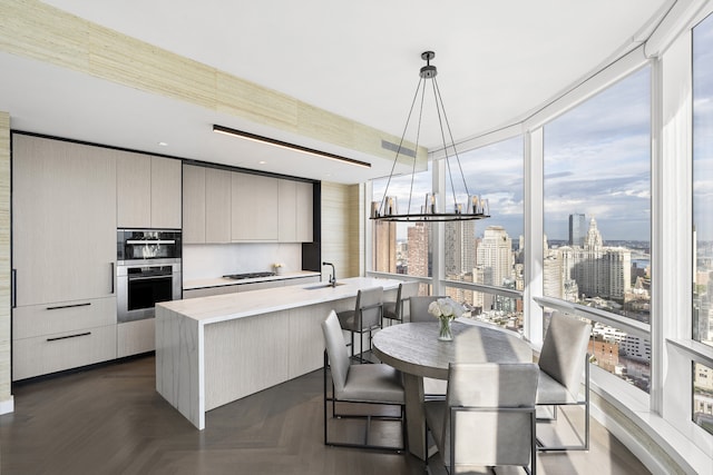 kitchen with a view of city, light countertops, modern cabinets, and a kitchen island with sink