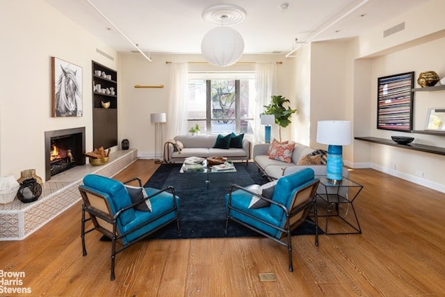 living room featuring wood-type flooring and built in features