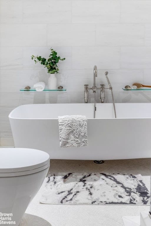 bathroom featuring toilet, tile walls, and a washtub