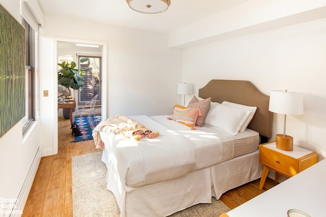 bedroom with light wood-type flooring, baseboard heating, and access to outside