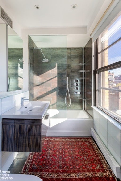 bathroom featuring tiled shower / bath, baseboard heating, and vanity