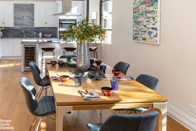 dining room with light wood-type flooring, beverage cooler, and sink