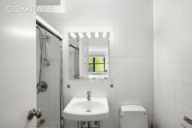 bathroom with a sink, toilet, tile walls, and shower / bathtub combination