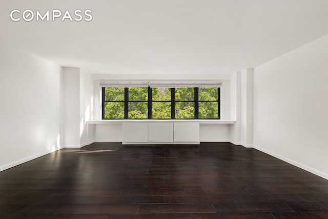 unfurnished room with a healthy amount of sunlight, baseboards, and hardwood / wood-style flooring