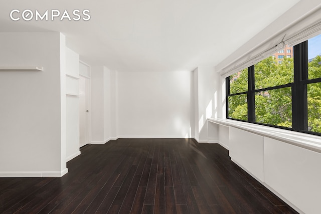 unfurnished room with baseboards and hardwood / wood-style floors