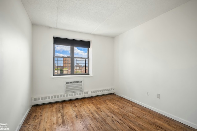 unfurnished room featuring baseboards, hardwood / wood-style floors, a wall mounted air conditioner, a textured ceiling, and a baseboard heating unit