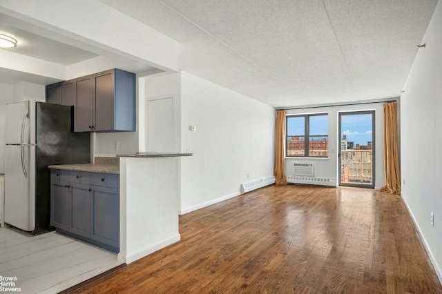 kitchen featuring baseboards, light wood-type flooring, freestanding refrigerator, and gray cabinetry