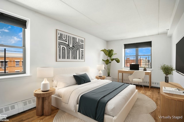 bedroom with baseboard heating and wood finished floors