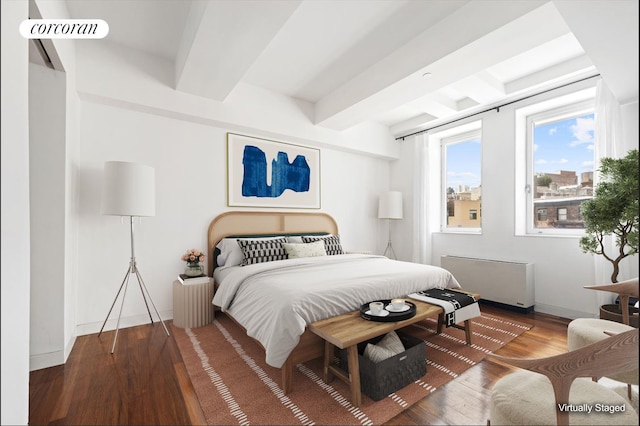 bedroom with radiator, baseboards, beamed ceiling, and wood finished floors