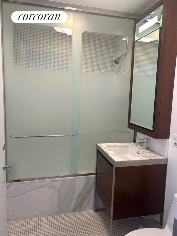 bathroom with toilet, shower / bath combination with glass door, and vanity