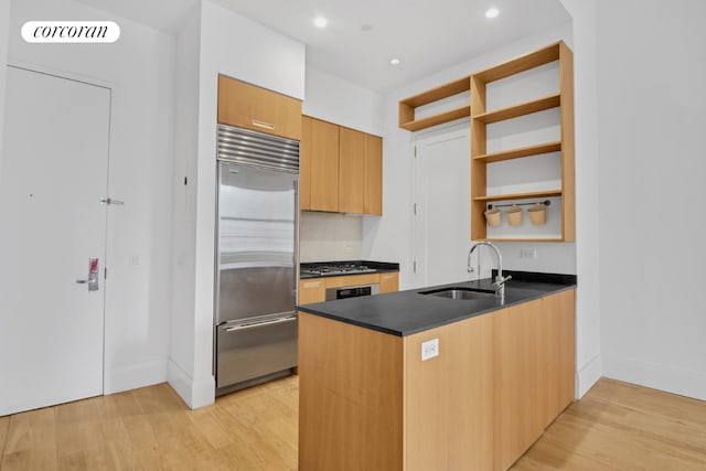 kitchen with stainless steel appliances, sink, light wood-type flooring, and kitchen peninsula