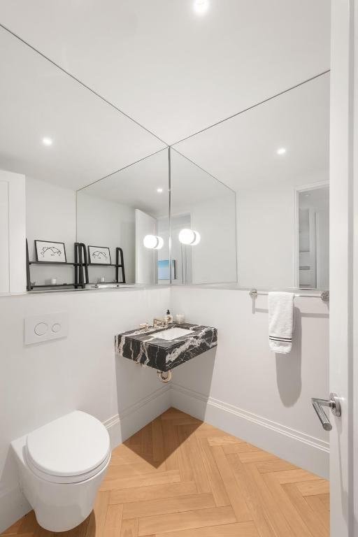 bathroom with parquet floors, toilet, and sink