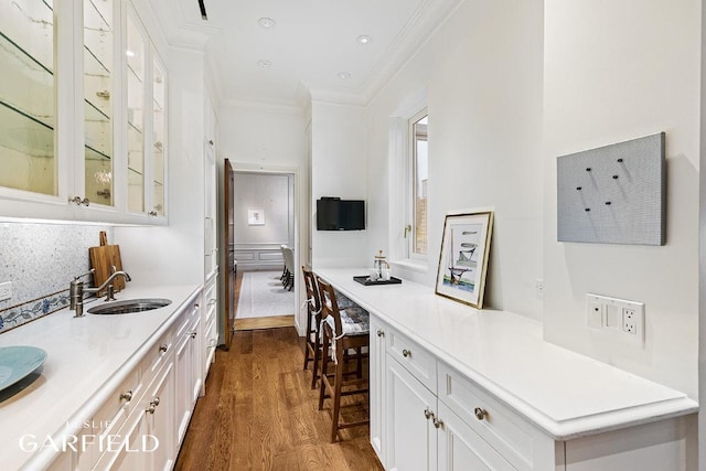 interior space featuring dark wood-type flooring, ornamental molding, sink, and white cabinets