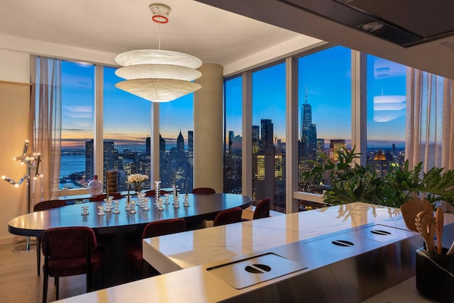 dining area featuring a water view, a wall of windows, and hardwood / wood-style flooring