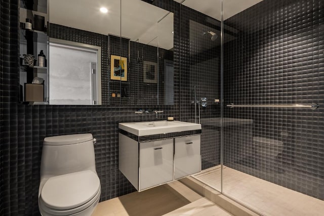 bathroom with vanity, toilet, a shower with door, and tile walls