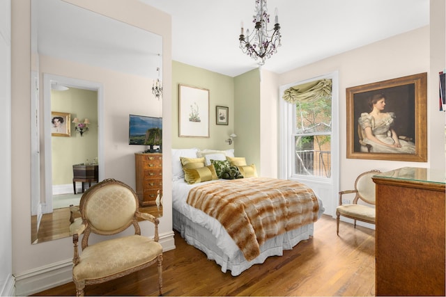 bedroom with baseboards, wood finished floors, and an inviting chandelier