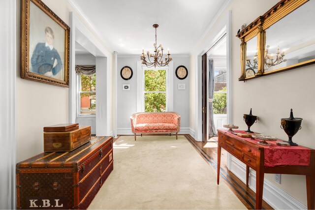 living area with a notable chandelier, baseboards, wood finished floors, and crown molding