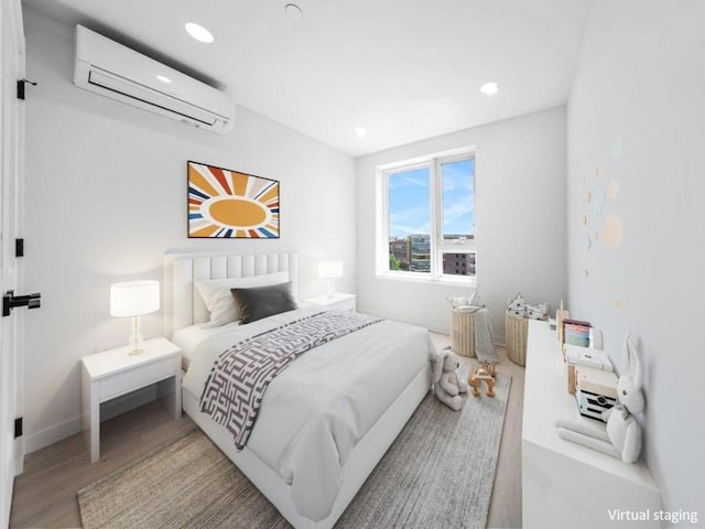 bedroom featuring a wall mounted AC and light hardwood / wood-style flooring