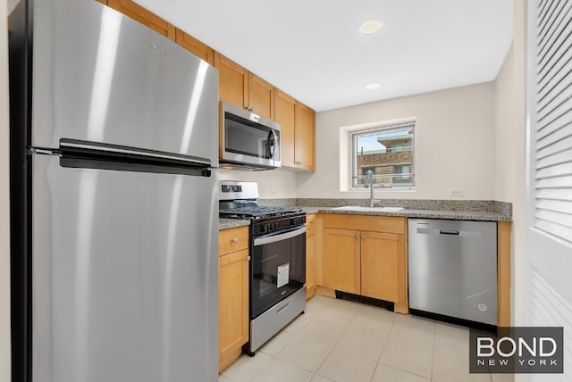 kitchen with stainless steel appliances, light stone countertops, and sink