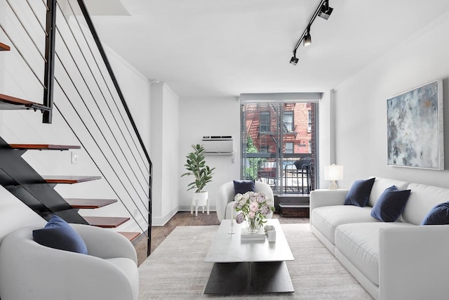 living room with light wood-type flooring, a wall mounted AC, and rail lighting