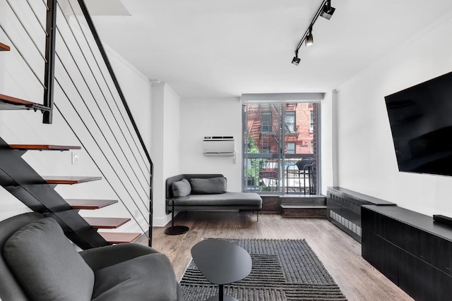 living room with an AC wall unit, rail lighting, light hardwood / wood-style flooring, and expansive windows