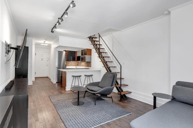 living room featuring crown molding, dark hardwood / wood-style flooring, and rail lighting