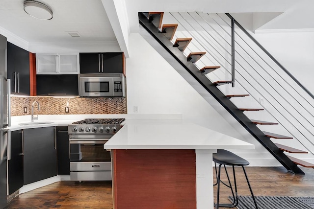 kitchen with tasteful backsplash, a kitchen bar, sink, stainless steel appliances, and dark hardwood / wood-style flooring