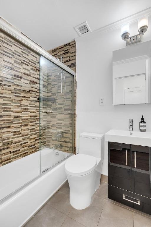 full bathroom with toilet, enclosed tub / shower combo, vanity, and tile patterned floors