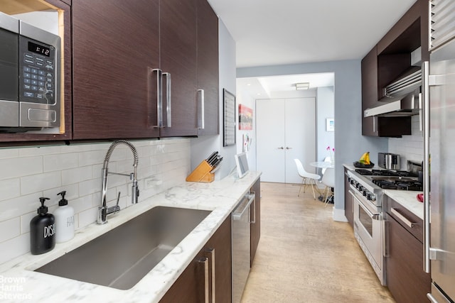 kitchen featuring tasteful backsplash, sink, light stone countertops, and high quality appliances