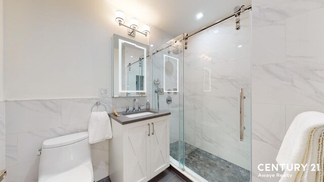 full bath with toilet, a marble finish shower, vanity, and tile walls