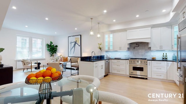 kitchen with decorative light fixtures, tasteful backsplash, light wood-type flooring, stainless steel appliances, and white cabinets