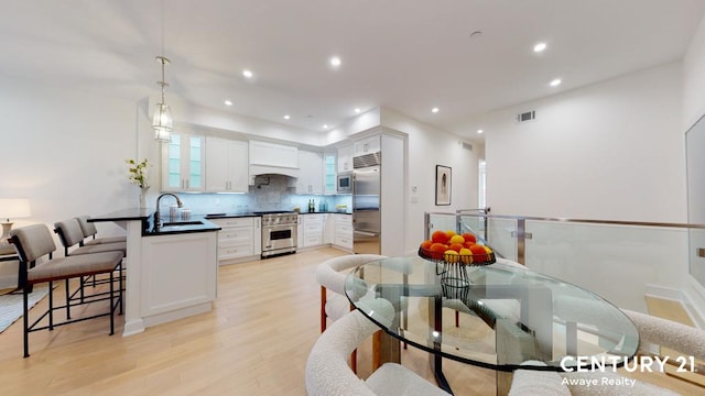 kitchen featuring decorative light fixtures, dark countertops, glass insert cabinets, white cabinets, and high quality appliances