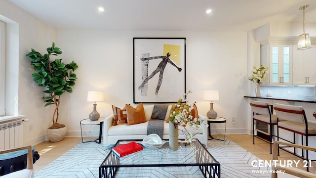 living area featuring baseboards, radiator heating unit, and recessed lighting