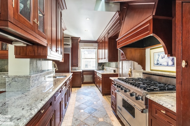 kitchen featuring custom exhaust hood, high end stove, sink, crown molding, and light stone countertops