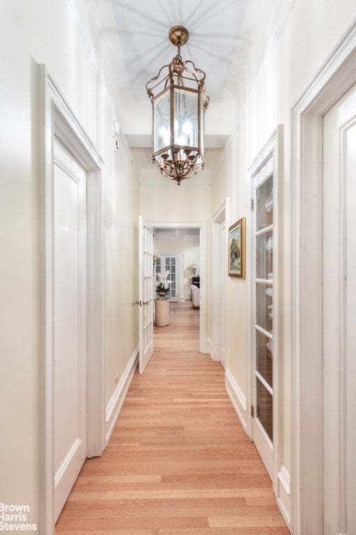 hall featuring an inviting chandelier and light hardwood / wood-style floors